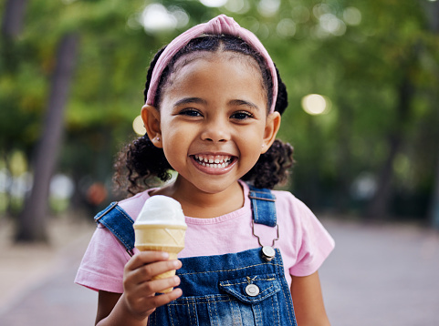 Portrait, young girl with ice cream in park, happy child outdoor with nature and freedom, dessert and smile. Travel, happiness and adventure, growth and childhood with family day out and youth mockup