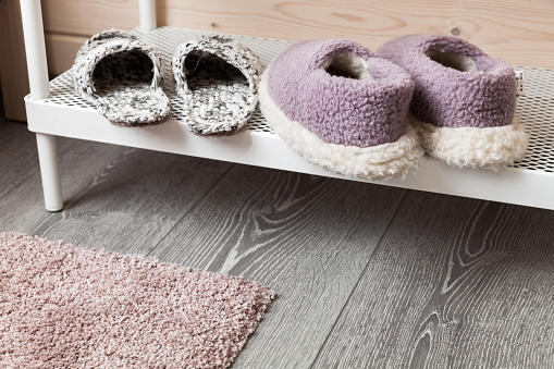 Woolen slippers stand on a white shelf, close up photo