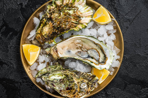 istock Fresh oysters with lemon on ice. Dark background. Top view 1474101974