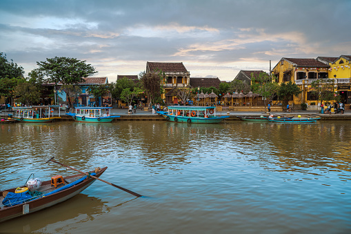 boats on Hoi An River in front of historic ancient town at sunset hour