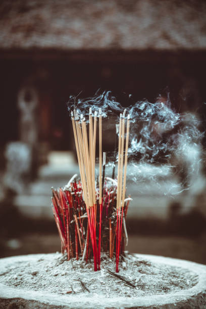 Incense sticks nad joss sticks burning and releasing aroma and white smoke in Asia