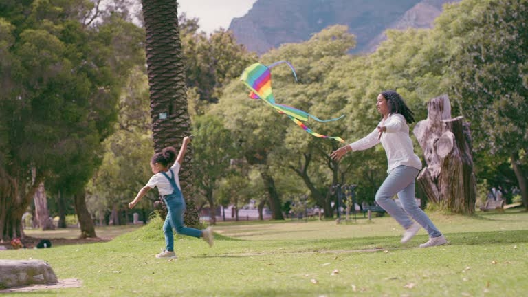 Nature, kite and mother running with her child in an outdoor park for exercise, bonding and fun. Field, active and mom playing with her girl kid in a green garden with freedom, adventure and energy.