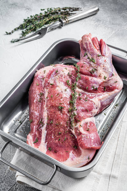 istock Ready for cooking lamb whole shoulder, raw leg meat on a grill pan with spices. Black background. Top view. Copy space 1474105295