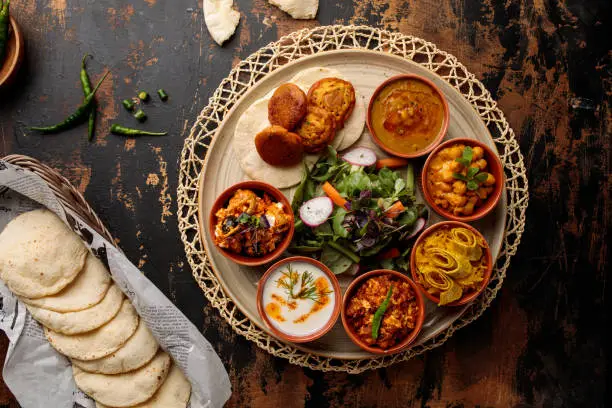 Photo of Bahraini Breakfast set with hummus, raita, salad, gravy, vegetable and bread served in dish isolated on table top view of arabic breakfast