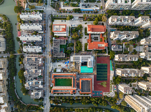 Aerial view of urban housing, schools, playgrounds, and green plants