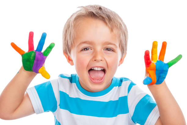istock Boy with hands painted in colorful paints ready to make hand prints, creative education concept 1474110889