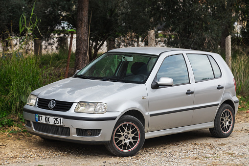 Side, Turkey -January 27, 2023:   silver Volkswagen Polo is parked  on the street on a warm summer day against the park