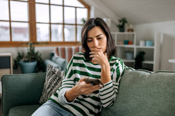 Concerned young woman using smart phone in a living room Concerned young hispanic lady looking on smartphone screen having finance savings stolen from bank as money fraud result money sad stock pictures, royalty-free photos & images