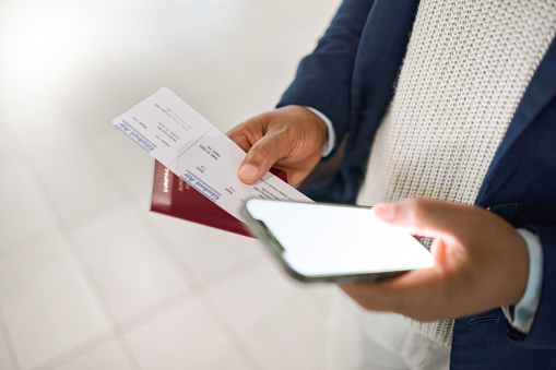 Hands, phone and passport with ticket for travel, schedule or checking flight times on mobile app at a airport. Hand of business employee holding smartphone, screen or ID document for trip or journey