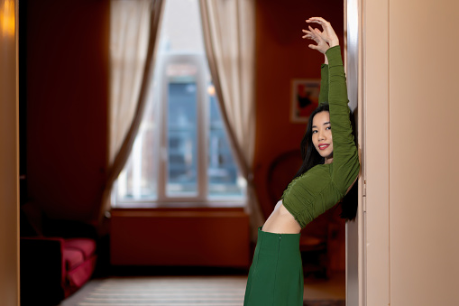 fashion portrait of asian female model - stylish woman posing with raised arms for a photo portrait in the room - vogue womanhood concept