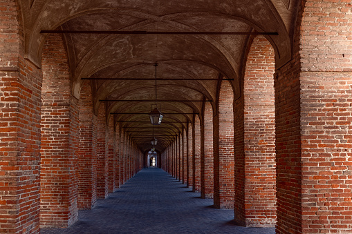 Red brick columns and arches in Galleria degli Antichi in Sabbioneta town. Lombardy, Italy