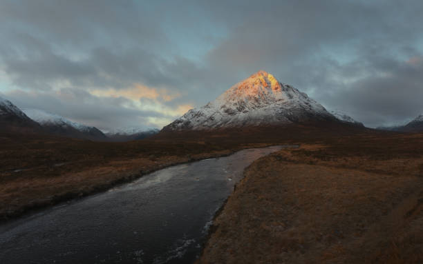 Landscape of the snowcapped Buachaille Etive Mor mountain and the Coe River at sunrise stock photo