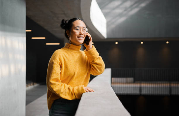 istock Phone call, conversation and mockup with an asian woman talking while standing in a hallway. Mobile, networking and communication with an attractive young female speaking on her smartphone indoor 1474125576
