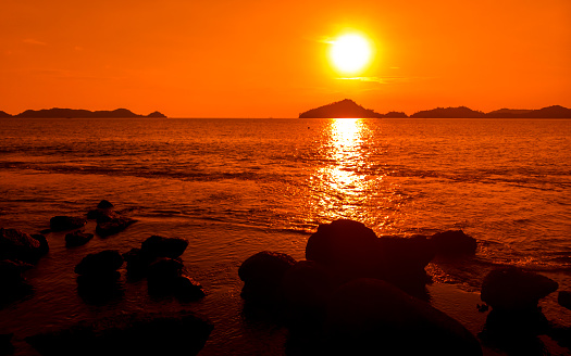 Ocean orange sunset landscape with rocks in silhouette