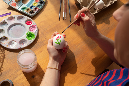 Woman painting easter eggs, easter decoration on table