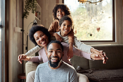 Happy black family having fun in the living room and looking at camera.