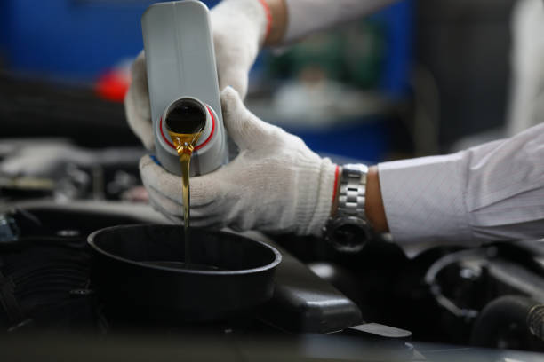 istock Auto mechanic pour engine oil into car engine closeup 1474128031