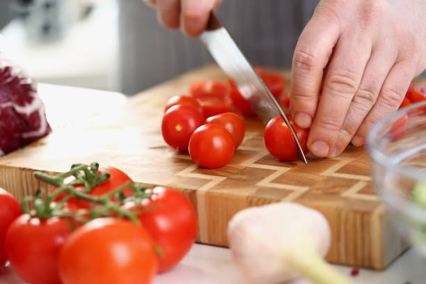 istock Chef cuts fresh ripe tomatoes on cutting board 1474132261