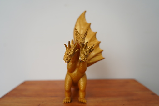 golden dragon ghidorah isolated on white background. On wooden table