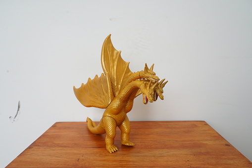 golden dragon ghidorah isolated on white background. On wooden table