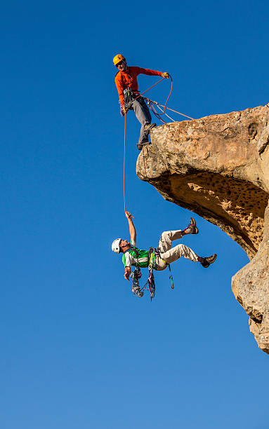 spadające wspinacz zapisane przez jego partnera. - extreme sports confidence adventure danger zdjęcia i obrazy z banku zdjęć