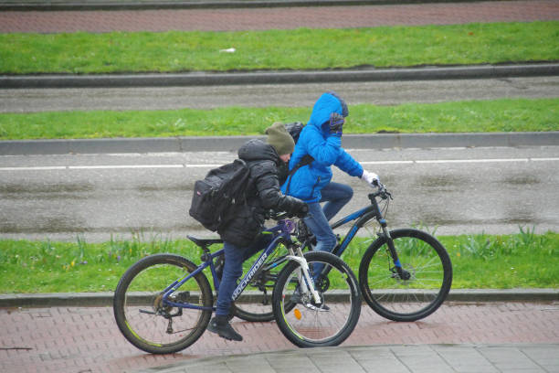 Brunssum, Netherlands -  March  12, 2023.  Teenagers biking on there way home in the rain.