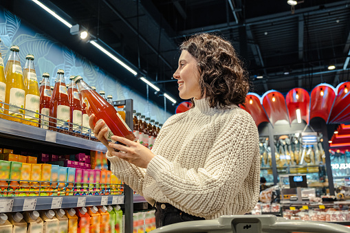 Woman picks juice in crowded supermarket
