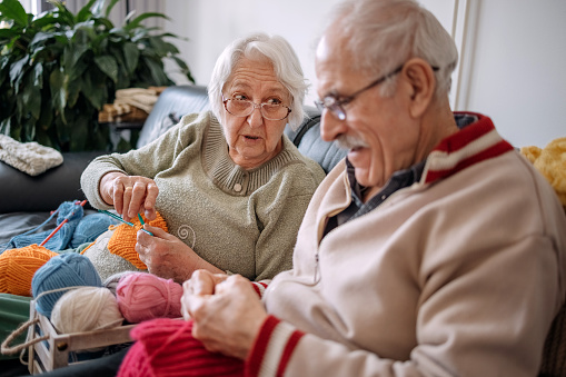 Senior woman teaching husband  how to knit