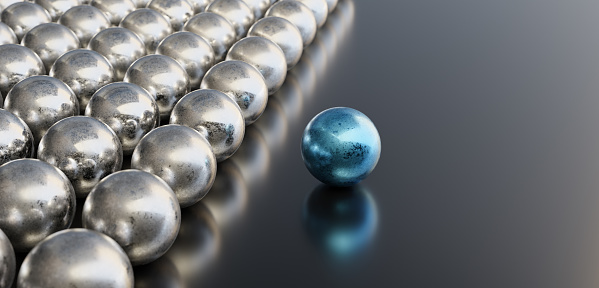 Leadership concept, blue leader ball, standing out from the crowd of silver balls, on black background with empty copy space on right side. 3D Rendering