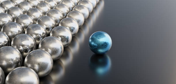 Leadership concept, blue leader ball, standing out from the crowd of silver balls, on black background with empty copy space on right side stock photo