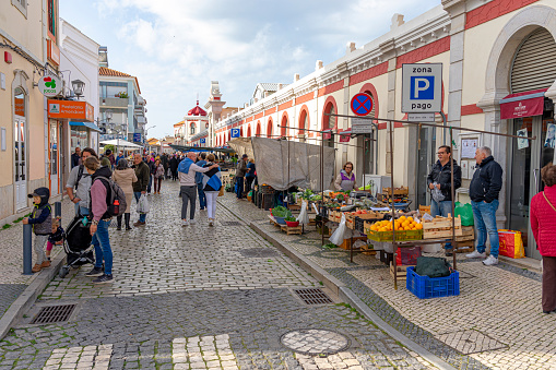 exterior of the municipal market of Loulé in the Algarve region during the day with customers and vendors at fruit and vegetable stalls.
