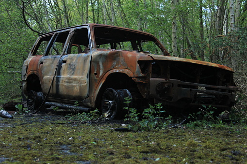 Wrecked and burnt out rusting 4x4 abandoned in the woods