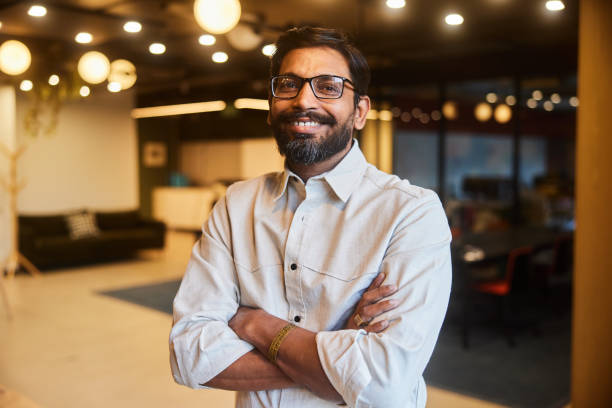 istock Businessman smiling while standing with his arms crossed in an office 1474144656
