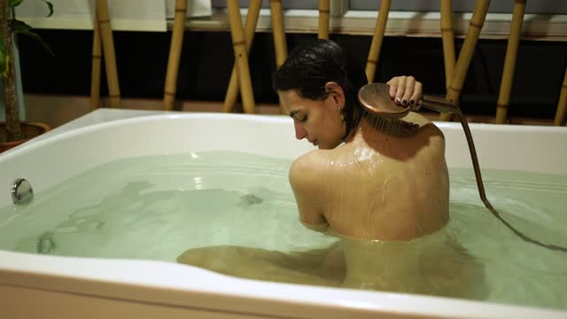 Latina woman is in a hot tub taking a delicious hot water bath