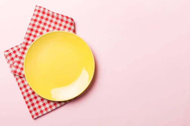 istock Top view on colored background empty round yellow plate on tablecloth for food. Empty dish on napkin with space for your design 1474151001
