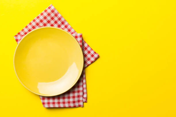 istock Top view on colored background empty round yellow plate on tablecloth for food. Empty dish on napkin with space for your design 1474151003