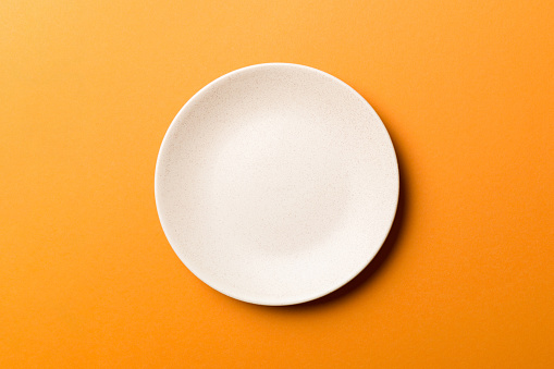 Top view of isolated of colored background empty round beige plate for food. Empty dish with space for your design.