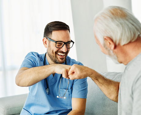 Doctor or nurse caregiver with senior man greeting each other at home or nursing home, partnership and cooperation concept