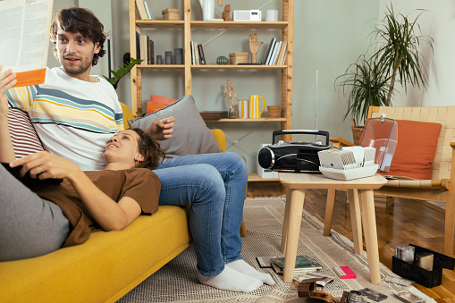 Young couple enjoying at home, checking their old cd's and records and enjoying music from the retro cd player