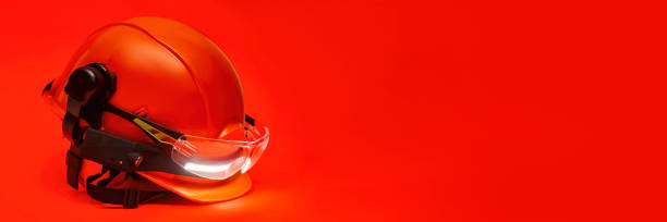 istock Protective goggles for eyes and construction helmet for head with earmuffs and headlamp on a red background. Construction tool and form for protection. 1474154093