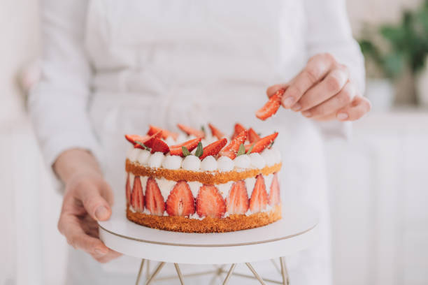 istock Confectioner in white uniform decorating mousse cake with strawberries 1474156263