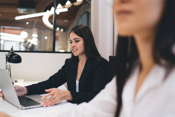 istock Cheerful young female employee using laptop at work 1474158489