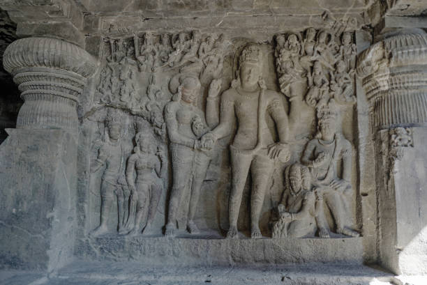 Ellora Caves Interiors Stone Sculptures of Shiva with a snake draped around him and his consort Parvati flanked with other deities stock photo