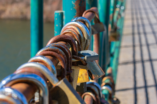 a padlocks on the metal railing of the bridge over the river