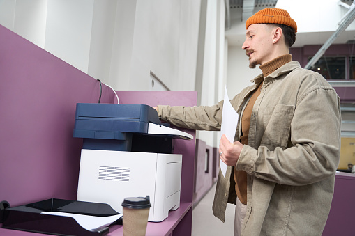 Concentrated office worker placing original into document feeder input tray of copy machine
