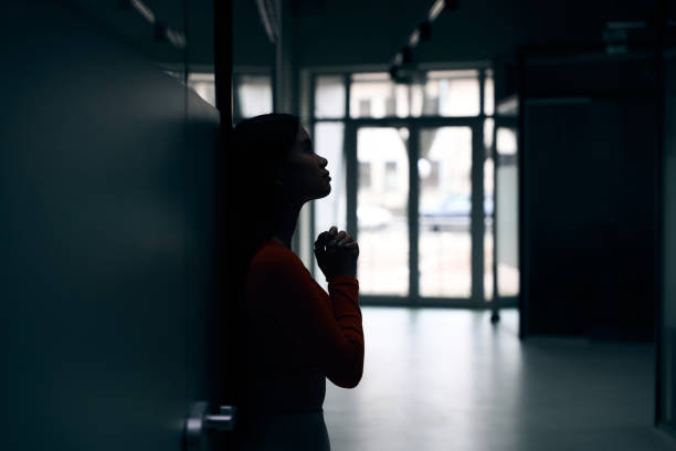 istock Despondent company employee praying in dark empty office corridor 1474164580