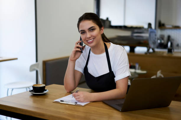 istock Smiling caucasian woman waitress talking on mobile phone about service delivery making notes in form, skilled professional female manager making smartphone call to banking service checking income 1474164796