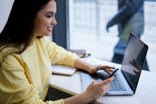 istock Positive female millennial making online shopping browse web page on laptop computer and using smartphone for transaction via banking app, prosperous hipster girl using technology on remote job 1474164840