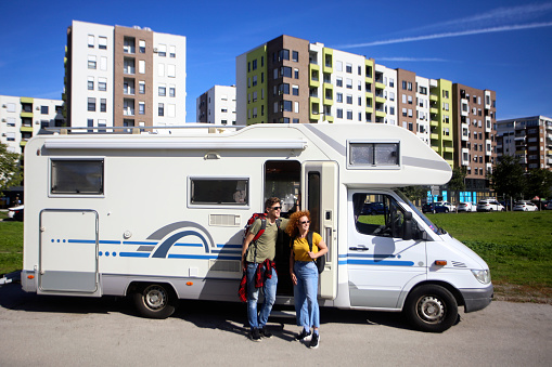Young couple in a city with a recreational vehicle (motor home). Both about 25 years old, Caucasian people.