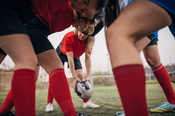 Group of women, female rugby players in a scrum on rugby field together outdoors.